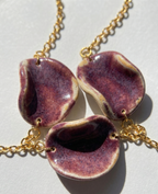 Akti plum ceramic necklace close up shot with gold chain, handmade organic petal forms in natural light 