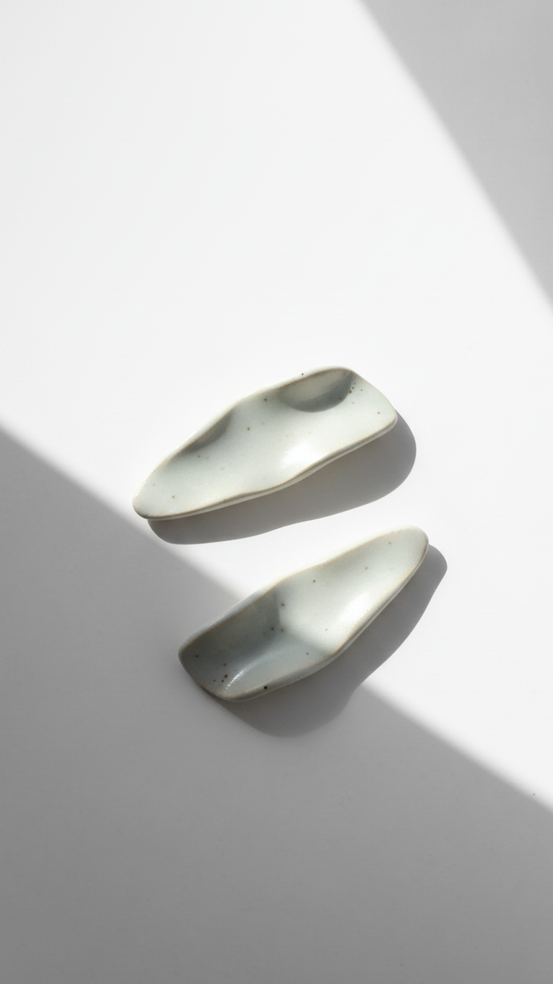 Galini ceramic statement earrings in white, handmade with organic wave-like form, shown in soft natural light and shadow
