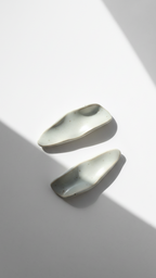 Galini ceramic statement earrings in white, handmade with organic wave-like form, shown in soft natural light and shadow