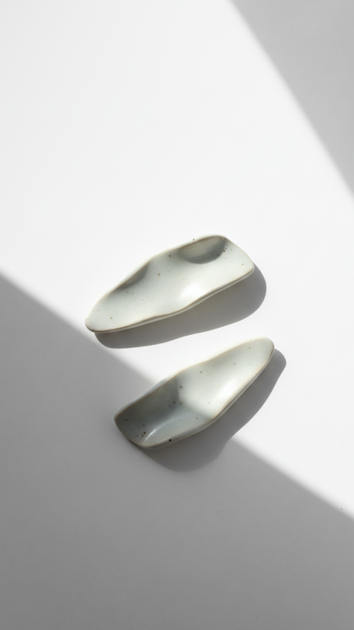 Galini ceramic statement earrings in white, handmade with organic wave-like form, shown in soft natural light and shadow