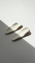 Galini ceramic statement earrings in white, handmade with organic wave-like form, shown in soft natural light and shadow