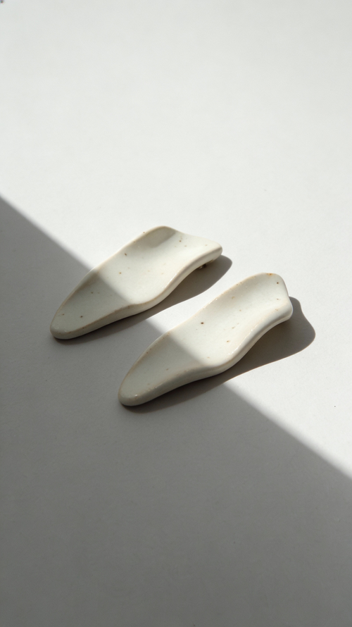 Galini ceramic statement earrings in white, handmade with organic wave-like form, shown in soft natural light and shadow
